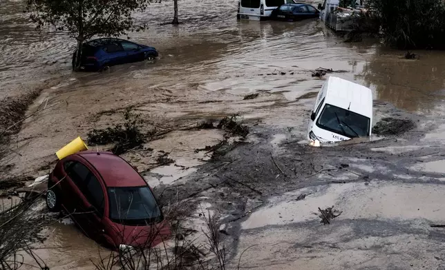 Cars are being swept away by the water, after floods preceded by heavy rains caused the river to overflow its banks in the town of Alora, Malaga, Spain, Tuesday, Oct. 29, 2024. (AP Photo/Gregorio Marrero)