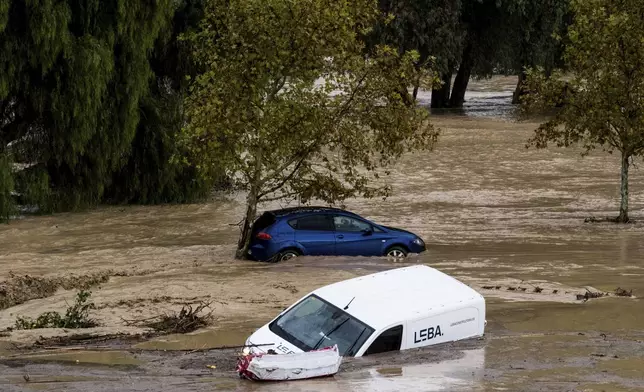 Cars are swept away by the water, after floods preceded by heavy rains caused the river to overflow its banks in the town of Alora, Malaga, Spain, Tuesday, Oct. 29, 2024. (AP Photo/Gregorio Marrero)