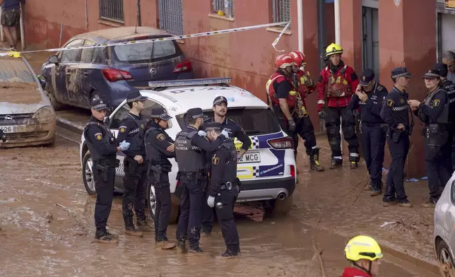 Members of the local police react to the news of one of their colleagues who died in the floods in Valencia, Spain, Thursday, Oct. 31, 2024. (AP Photo/Alberto Saiz)