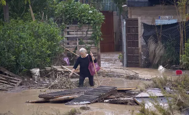 A woman walks through flooded streets in Valencia, Spain, Wednesday, Oct. 30, 2024. (AP Photo/Alberto Saiz)