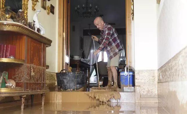 A man cleans his house affected by floods in Valencia, Spain, Wednesday, Oct. 30, 2024. (AP Photo/Alberto Saiz)