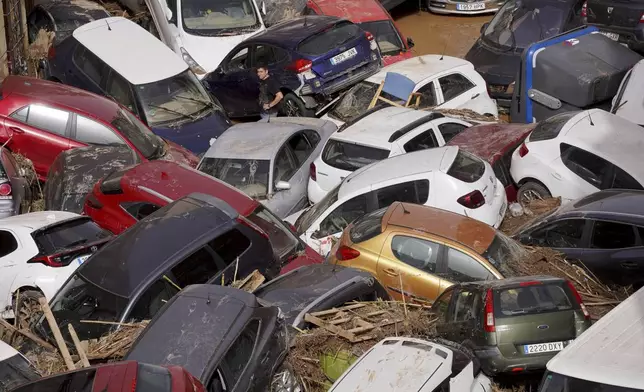 Residents look at cars piled up after being swept away by floods in Valencia, Spain, Wednesday, Oct. 30, 2024. (AP Photo/Alberto Saiz)