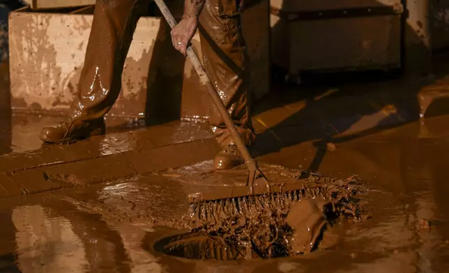 A person removes mud after the floods in Utiel, Spain, Wednesday, Oct. 30, 2024. (AP Photo/Manu Fernandez)