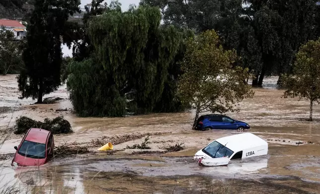 Cars are being swept away by the water, after floods preceded by heavy rains caused the river to overflow its banks in the town of Alora, Malaga, Tuesday, Oct. 29, 2024. (AP Photo/Gregorio Marrero)