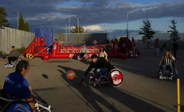 Fans try to play soccer in wheelchairs before going to see the Champions League opening phase soccer match between Atletico Madrid and Lille at the Metropolitano stadium in Madrid, Spain, Wednesday, Oct. 23, 2024. (AP Photo/Manu Fernandez)