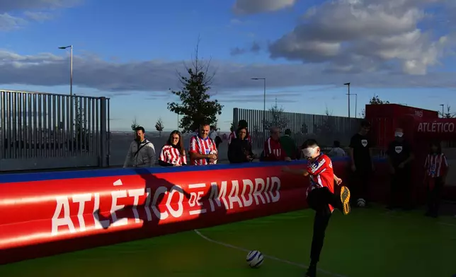 A fan tries to kick a ball with a blindfold on before going to see the Champions League opening phase soccer match between Atletico Madrid and Lille at the Metropolitano stadium in Madrid, Spain, Wednesday, Oct. 23, 2024. (AP Photo/Manu Fernandez)