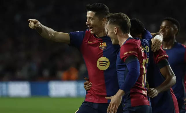 Barcelona's Robert Lewandowski, left, celebrates with teammates after scoring the opening goal from the penalty spot during a Spanish La Liga soccer match between Barcelona and Sevilla at the Olimpic Lluis Companys stadium in Barcelona, Spain, Sunday, Oct. 20, 2024. (AP Photo/Joan Monfort)