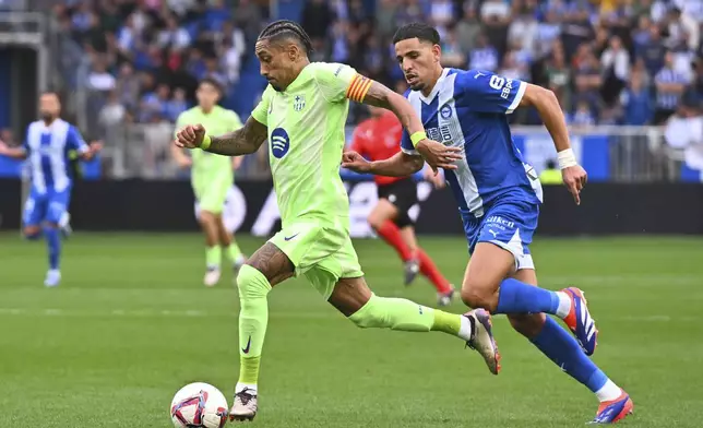 Barcelona's Raphinha, left, controls a ball challenged by Alaves' Abdel Abqar during a Spanish La Liga soccer match at the Mendizorroza stadium in Vitoria-Gasteiz, Spain, Sunday, Oct. 6, 2024. (AP Photo/Miguel Oses)