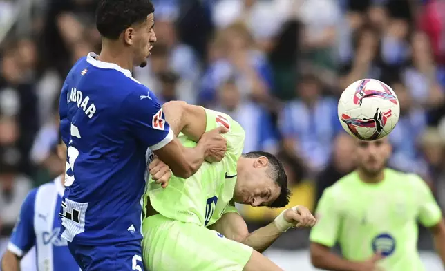 Barcelona's Robert Lewandowski, right, and Alaves' Abdel Abqar battle for the ball during a Spanish La Liga soccer match at the Mendizorroza stadium in Vitoria-Gasteiz, Spain, Sunday, Oct. 6, 2024. (AP Photo/Miguel Oses)