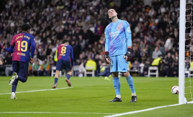 Real Madrid's goalkeeper Andriy Lunin reacts after Barcelona's Robert Lewandowski scored his side's second goal during a Spanish La Liga soccer match between Real Madrid and Barcelona at the Santiago Bernabeu stadium in Madrid, Spain, Saturday, Oct. 26, 2024. (AP Photo/Manu Fernandez)