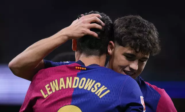 Barcelona's Robert Lewandowski, left, celebrates after scoring his side's opening goal during a Spanish La Liga soccer match between Real Madrid and Barcelona at the Santiago Bernabeu stadium in Madrid, Spain, Saturday, Oct. 26, 2024. (AP Photo/Manu Fernandez)