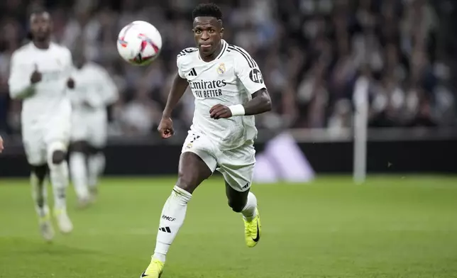 Real Madrid's Vinicius Junior runs with the ball during a Spanish La Liga soccer match between Real Madrid and Barcelona at the Santiago Bernabeu stadium in Madrid, Spain, Saturday, Oct. 26, 2024. (AP Photo/Bernat Armangue)