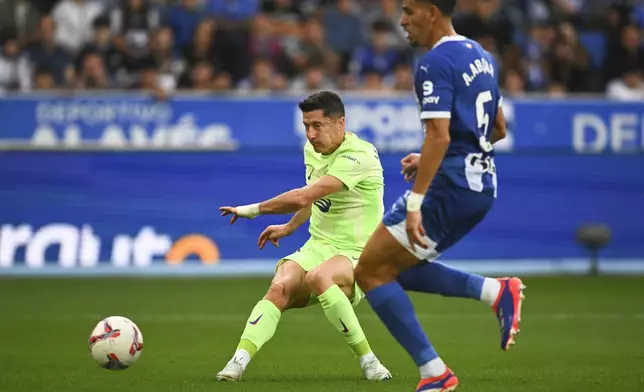 Barcelona's Robert Lewandowski, back, scores his side's 3rd goal against Alaves during a Spanish La Liga soccer match at the Mendizorroza stadium in Vitoria-Gasteiz, Spain, Sunday, Oct. 6, 2024. (AP Photo/Miguel Oses)