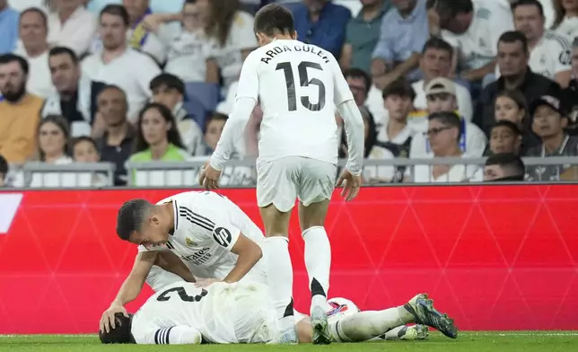 Real Madrid's Lucas Vazquez checks on his teammate Dani Carvajal during the La Liga soccer match between Real Madrid and Villareal in Madrid, Spain, on Saturday, Oct. 5, 2024. (AP Photo/Bernat Armangue)