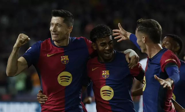 Barcelona's Robert Lewandowski, left, celebrates with teammates after scoring the opening goal from the penalty spot during a Spanish La Liga soccer match between Barcelona and Sevilla at the Olimpic Lluis Companys stadium in Barcelona, Spain, Sunday, Oct. 20, 2024. (AP Photo/Joan Monfort)