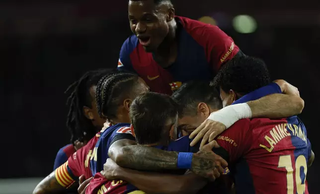 Barcelona's Robert Lewandowski celebrates with teammates after scoring the opening goal from the penalty spot during a Spanish La Liga soccer match between Barcelona and Sevilla at the Olimpic Lluis Companys stadium in Barcelona, Spain, Sunday, Oct. 20, 2024. (AP Photo/Joan Monfort)