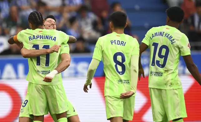 Barcelona's Robert Lewandowski, left back, celebrates after scoring his side's 2nd goal against Alaves during a Spanish La Liga soccer match at the Mendizorroza stadium in Vitoria-Gasteiz, Spain, Sunday, Oct. 6, 2024. (AP Photo/Miguel Oses)