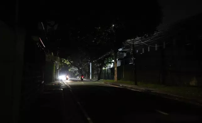 Vehicles pass by a dimly lit portion of Balete Drive in Quezon City, Philippines, Friday, Oct. 25, 2024. (AP Photo/Aaron Favila)