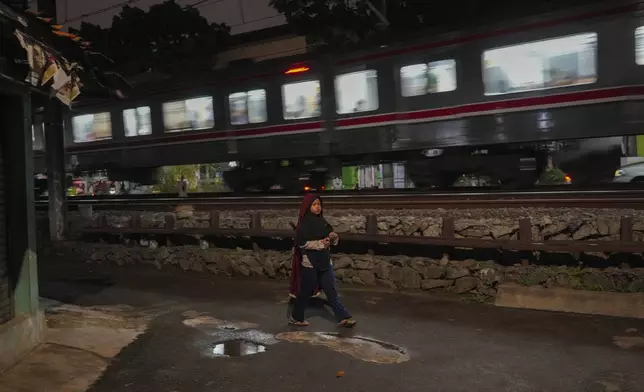 A young girl walks next to a railway track near the scene of a 1987 train collision that killed 139 people in Bintaro, Indonesia, Friday, Oct. 25, 2024. (AP Photo/Tatan Syuflana)