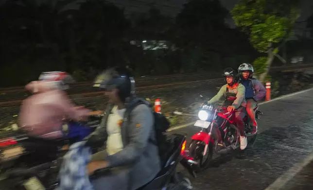 Motorists ride near a railway track where two commuter trains collided in 1987, killing 139 people, in Bintaro, Indonesia, Friday, Oct. 25, 2024. (AP Photo/Tatan Syuflana)