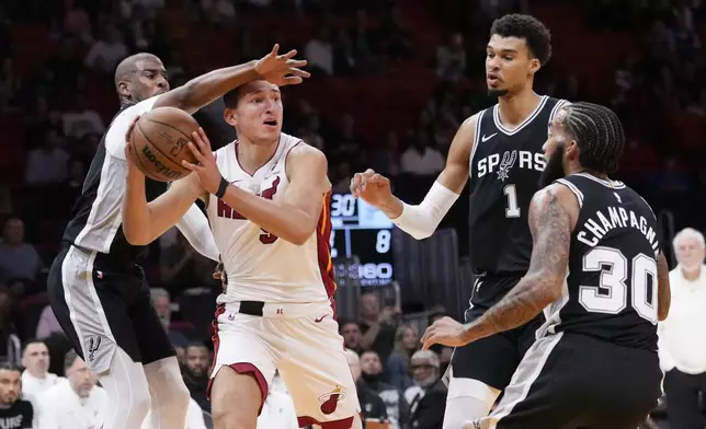 Miami Heat forward Nikola Jovic, second from left, looks for an opening past San Antonio Spurs guard Chris Paul, left, forwards Victor Wembanyama (1) and Julian Champagnie (30) during the first half of an NBA preseason basketball game, Tuesday, Oct. 15, 2024, in Miami. (AP Photo/Wilfredo Lee)