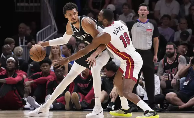 San Antonio Spurs forward Victor Wembanyama (1) drives up against Miami Heat guard Alec Burks (18) during the first half of an NBA preseason basketball game, Tuesday, Oct. 15, 2024, in Miami. (AP Photo/Wilfredo Lee)