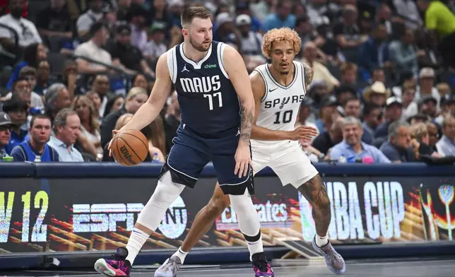 Dallas Mavericks' guard Luka Doncic, left, is defended by San Antonio Spurs forward Jeremy Sochan, right, during the first half of an NBA basketball game, Thursday, Oct. 24, 2024, in Dallas, Texas. (AP Photo/Albert Pena)