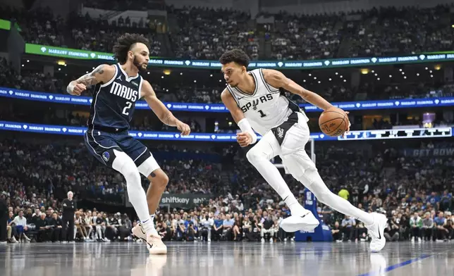 San Antonio Spurs' Victor Wembanyama, right, drives against Dallas Mavericks' Dereck Lively II, left, during the first half of an NBA basketball game, Thursday, Oct. 24, 2024, in Dallas, Texas. (AP Photo/Albert Pena)