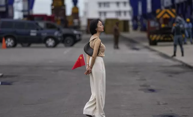 A Chinese national residing in Sri Lanka holds a national flag as she waits to welcome the Chinese navy's sail training warship Po Lang at a port in Colombo, Sri Lanka, Tuesday, Oct. 8, 2024. (AP Photo/Eranga Jayawardena)