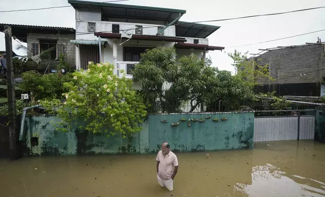 A man wades through his flooded neighborhood in Colombo, Sri Lanka, Monday, Oct. 14, 2024. (AP Photo/Eranga Jayawardena)