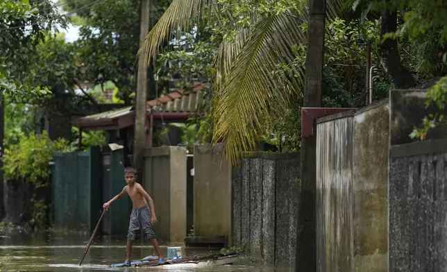 A boy plays with a makeshift raft at a flooded neighborhood in Colombo, Sri Lanka, Monday, Oct. 14, 2024. (AP Photo/Eranga Jayawardena)