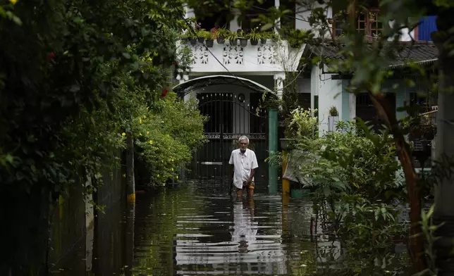 A man wades through water outside his flooded house in Colombo, Sri Lanka, Sunday, Oct. 13, 2024. (AP Photo/Eranga Jayawardena)