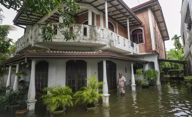 A man stands by his flooded house in Colombo, Sri Lanka, Monday, Oct. 14, 2024. (AP Photo/Eranga Jayawardena)