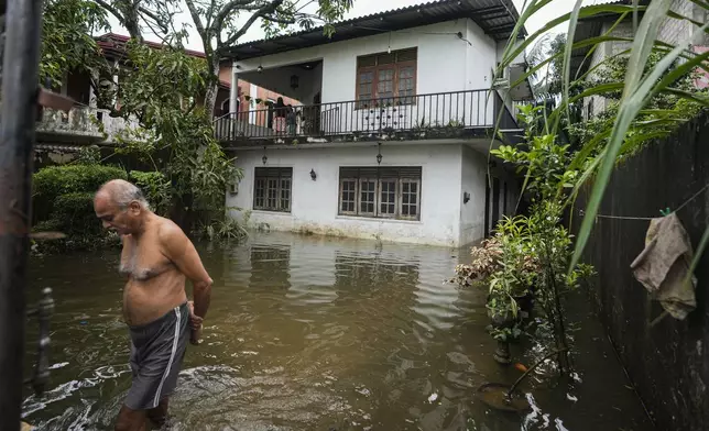 A man wades through his flooded neighborhood in Colombo, Sri Lanka, Monday, Oct. 14, 2024. (AP Photo/Eranga Jayawardena)