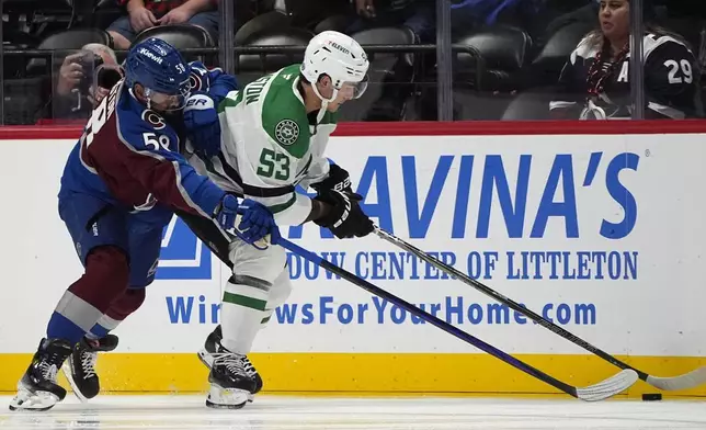 Colorado Avalanche defenseman Oliver Kylington, left, fights for control of the puck with Dallas Stars center Wyatt Johnston, right, in the first period of an NHL preseason hockey game Monday, Sept. 23, 2024, in Denver. (AP Photo/David Zalubowski)