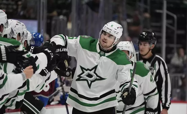 Dallas Stars defenseman Lian Bichsel is congratulated as he passes the team box after he scored the winning goal as time ran out in an NHL preseason hockey game against the Colorado Avalanche, Monday, Sept. 23, 2024, in Denver. (AP Photo/David Zalubowski)