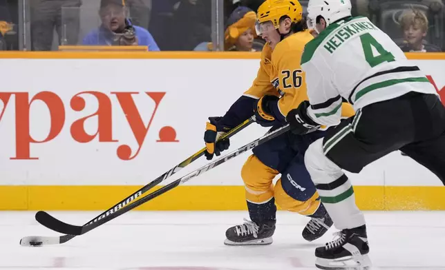 Nashville Predators center Philip Tomasino (26) skates the puck past Dallas Stars defenseman Miro Heiskanen (4) during the second period of an NHL hockey game Thursday, Oct. 10, 2024, in Nashville, Tenn. (AP Photo/George Walker IV)