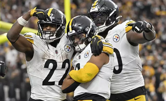 Pittsburgh Steelers quarterback Justin Fields, middle, is congratulated by running back Najee Harris (22) and tight end Darnell Washington after scoring against the Las Vegas Raiders during the second half of an NFL football game in Las Vegas, Sunday, Oct. 13, 2024. (AP Photo/David Becker)