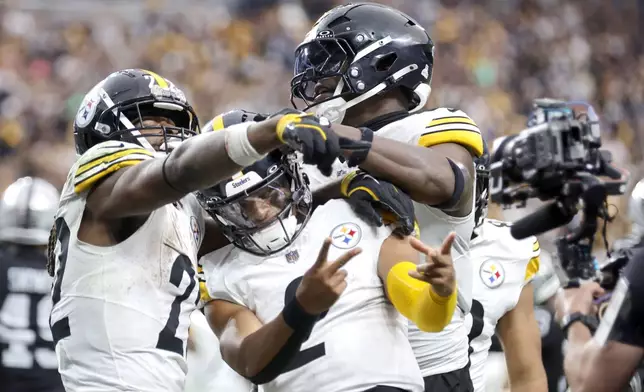 Pittsburgh Steelers quarterback Justin Fields, center, poses with running back Najee Harris, left, and tight end Darnell Washington, right, after scoring a touchdown against the Las Vegas Raiders during the second half of an NFL football game Sunday, Oct. 13, 2024, in Las Vegas. (Steve Marcus/Las Vegas Sun via AP)