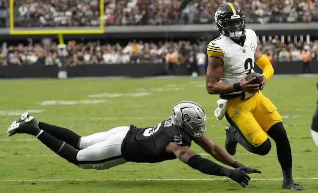 Pittsburgh Steelers quarterback Justin Fields, right, runs for a touchdown past Las Vegas Raiders defensive end Tyree Wilson during the first half of an NFL football game in Las Vegas, Sunday, Oct. 13, 2024. (AP Photo/John Locher)