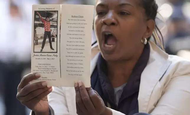 A woman yells and holds up a picture of Jordan Neely just before Daniel Penny arrives to Manhattan criminal court in New York, Monday, Oct. 21, 2024. (AP Photo/Seth Wenig)