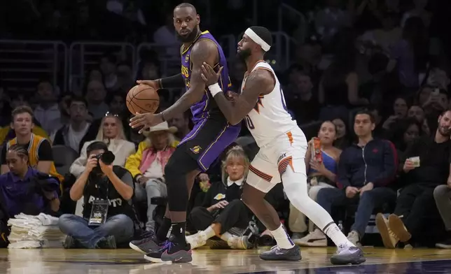 Los Angeles Lakers forward LeBron James, left, dribbles against Phoenix Suns forward Royce O'Neale, right, during the first half of an NBA basketball game against the in Los Angeles, Friday, Oct. 25, 2024. (AP Photo/Eric Thayer)