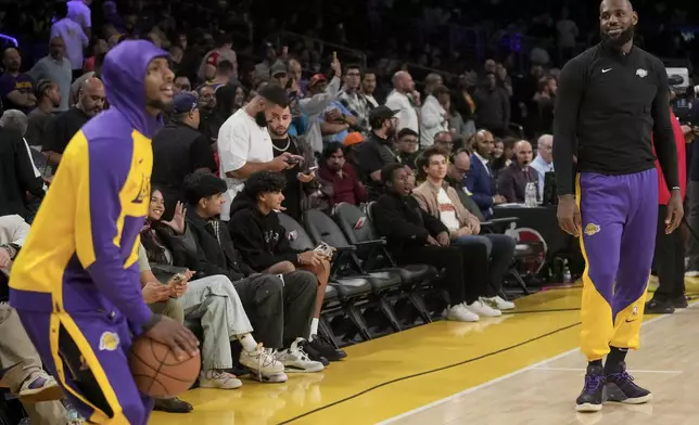 Los Angeles Lakers guard Bronny James shoots as forward LeBron James (23) watches on before an NBA basketball game against the Phoenix Suns in Los Angeles, Friday, Oct. 25, 2024. (AP Photo/Eric Thayer)