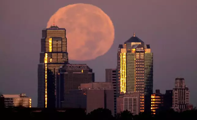 The moon rises beyond downtown buildings Thursday, Oct. 17, 2024, in Kansas City, Mo. (AP Photo/Charlie Riedel)