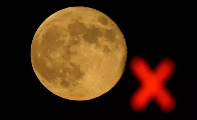 The waning supermoon rises beyond a train signal Thursday, Oct. 17, 2024, in Lenexa, Kan. (AP Photo/Charlie Riedel)