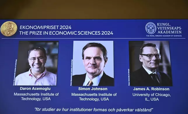 The Nobel memorial prize in economics awarded to Daron Acemoglu, Simon Johnson and James A Robinson, seen on screen, during a press meeting at the Royal Swedish Academy of Sciences in Stockholm, Sweden, Monday Oct. 14, 2024. (Christine Olsson/TT News Agency via AP)