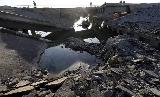 A Syrian man passes by a bridge that links to Lebanon which was destroyed on Oct. 24 by an Israeli airstrike, in Qusair, Syria, Sunday, Oct. 27, 2024. (AP Photo/Omar Sanadiki)