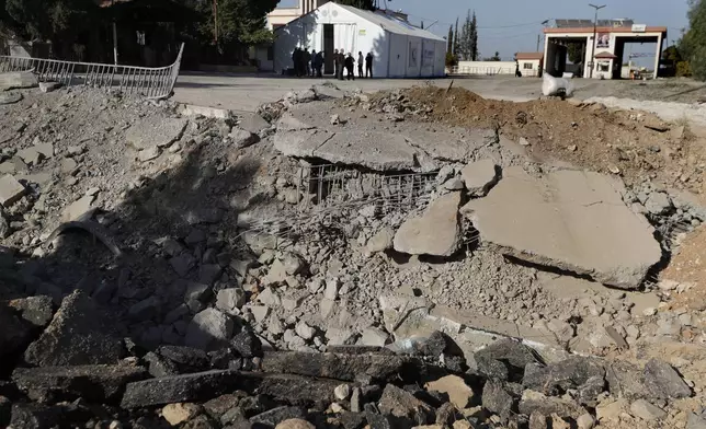 People gather near a crater caused by an Israeli airstrike, which blocks the road between the Lebanese and the Syrian crossing points, in Jousieh, Syria, Sunday, Oct. 27, 2024. (AP Photo/Omar Sanadiki)