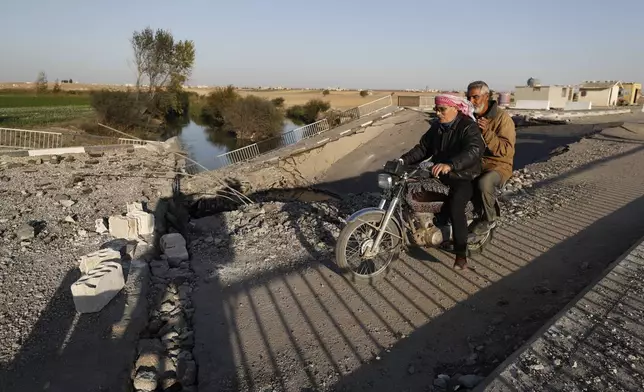 Syrian citizens ride a motorcycle as they cross a bridge that links to Lebanon which was destroyed on Oct. 24 by an Israeli airstrike, in Qusair, Syria, Sunday, Oct. 27, 2024. (AP Photo/Omar Sanadiki)