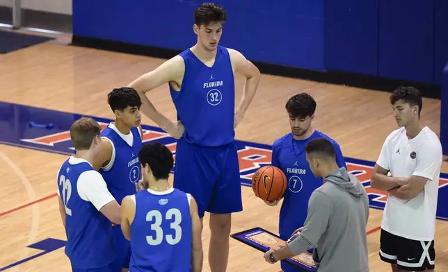 Olivier Rioux, back center, a 7-foot-9 NCAA college basketball player at Florida, gathers with coaches and teammates at the team's practice, Friday, Oct. 18, 2024, in Gainesville, Fla. (AP Photo/John Raoux)